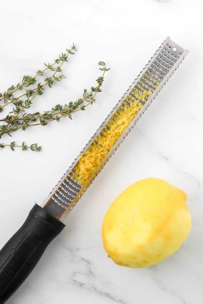 Fresh thyme sprigs, a lemon zester with lemon zest and lemon