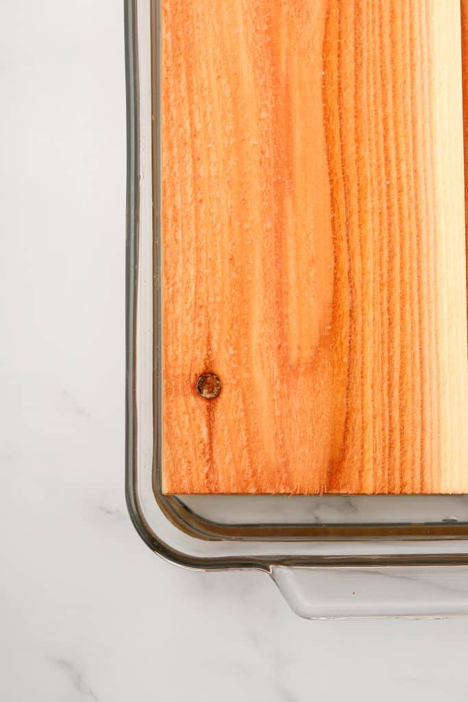 A close up of a cedar plank soaking in water