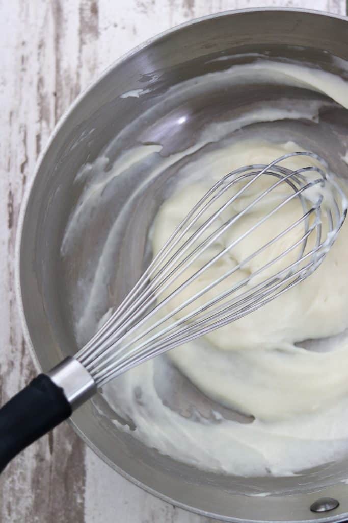 Vanilla custard in a saucepan with a whisk