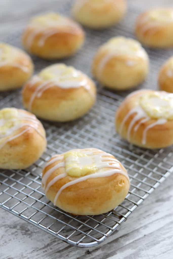 Buns filled with vanilla custard and drizzled with glaze on a cooling rack