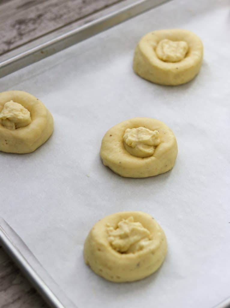 Unbaked buns filled with vanilla custard on a sheet pan