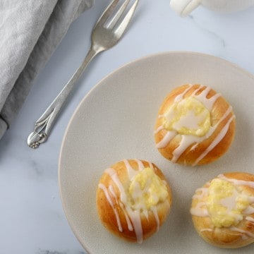 Custard filled buns on a plate with a fork and napkin