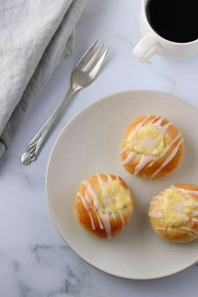 Custard filled buns on a plate with a fork and napkin