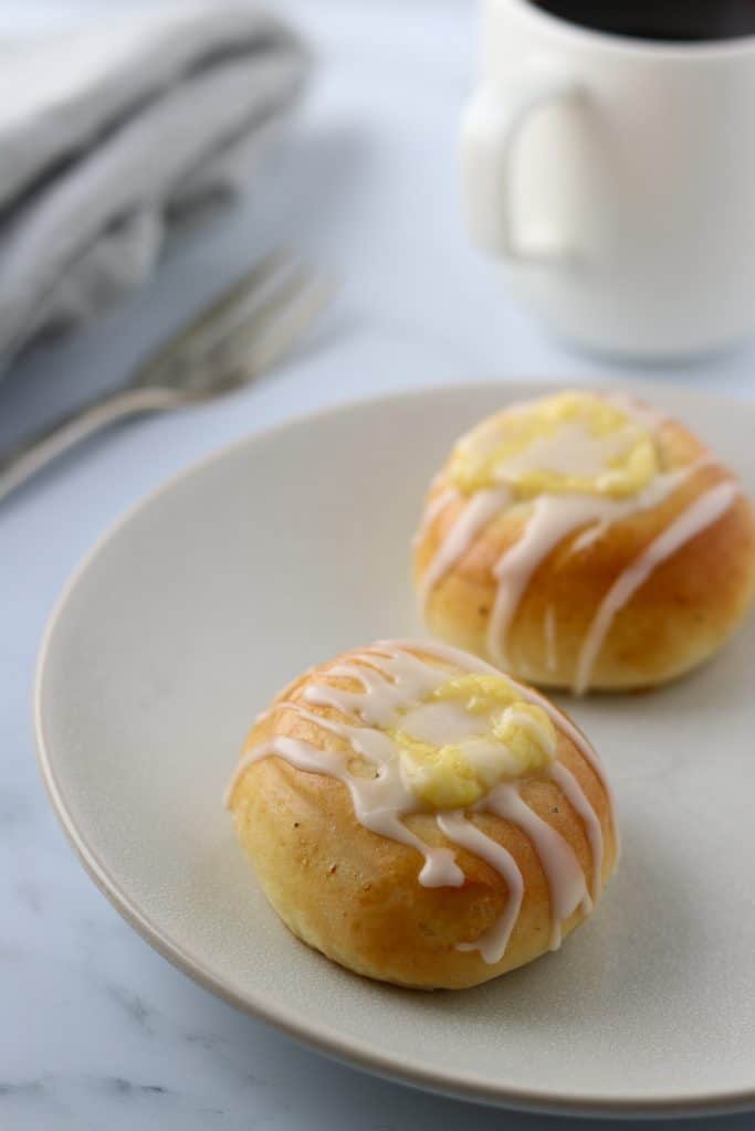 Vanilla custard buns on a plate with a fork and mug