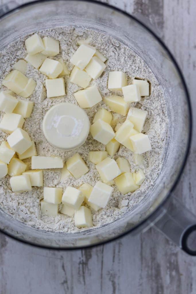 A close up of flour and cubes of butter in a food processor