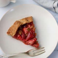 A slice of strawberry rhubarb galette on a plate with a fork