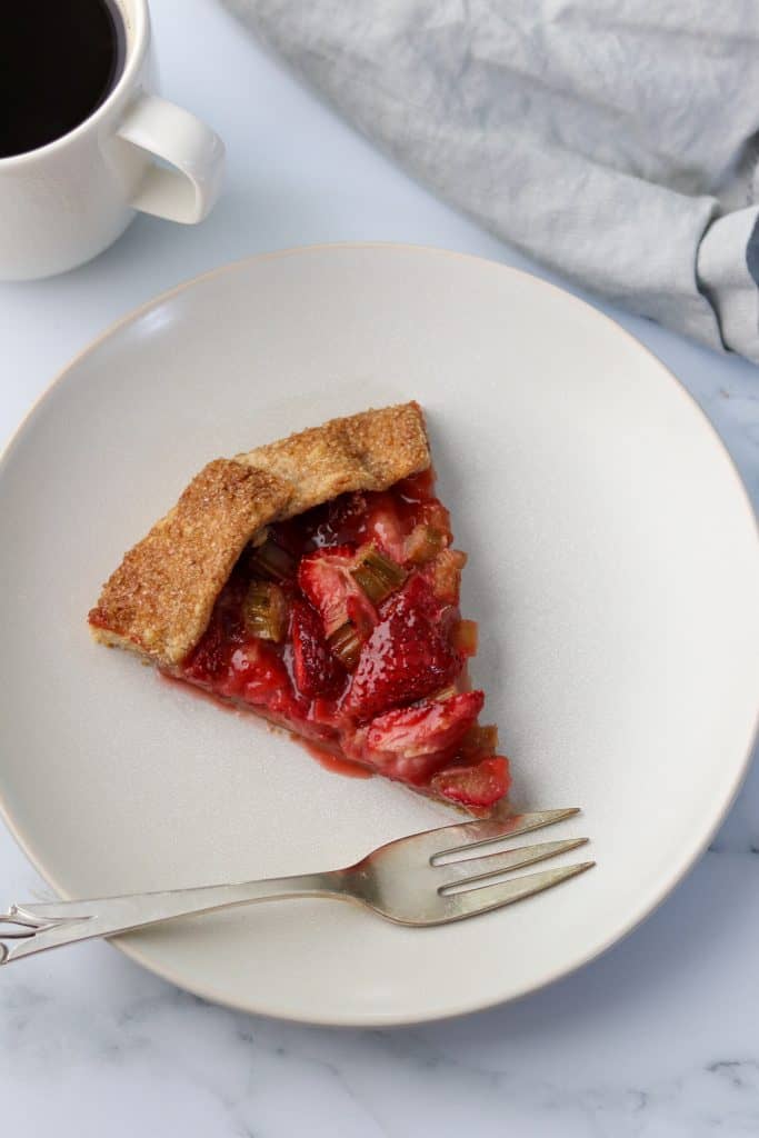 A slice of strawberry rhubarb galette on a plate with a fork