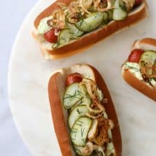 Hot dogs on buns with pickled cucumbers on a plate