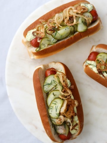 Hot dogs on buns with pickled cucumbers on a plate