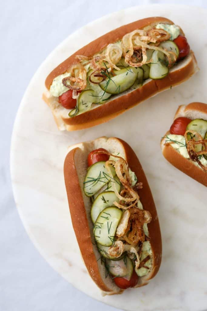Hot dogs on buns with pickled cucumbers on a plate