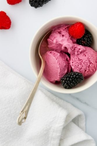 Frozen berry skyr yogurt in a bowl with fresh berries and a spoon