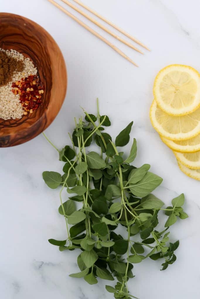 Fresh herbs, lemon slices and a bowl of spices