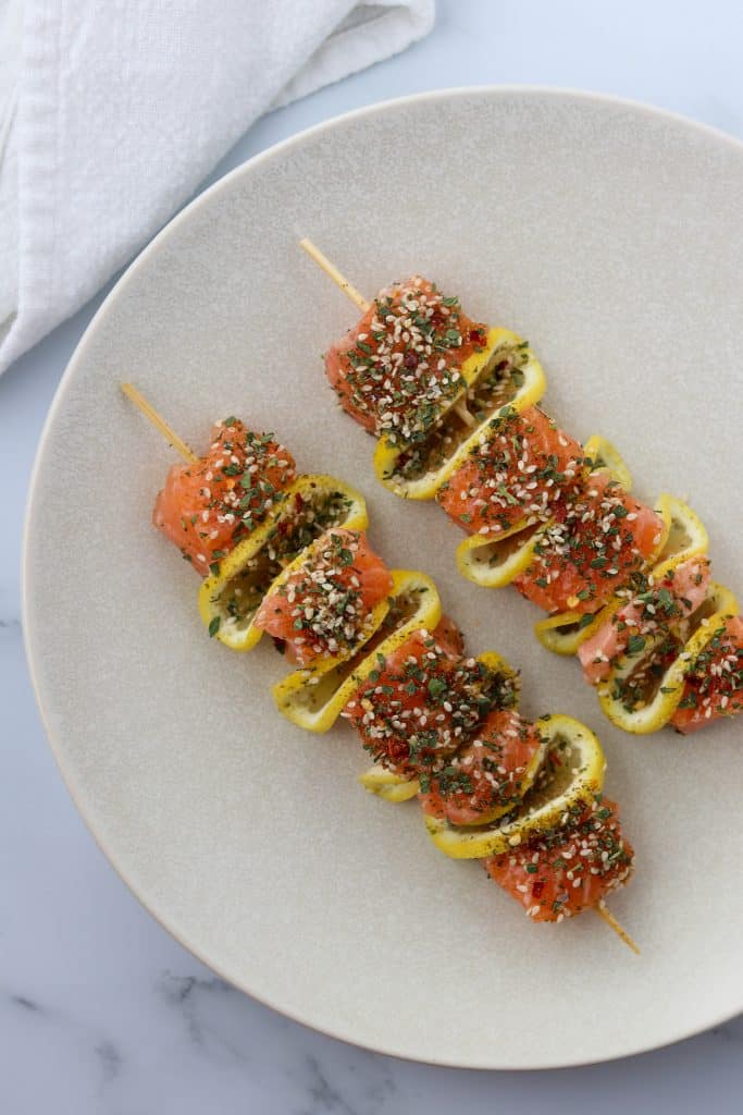 A plate with salmon skewers with lemon slices