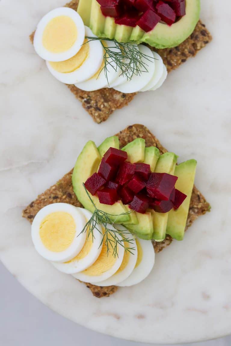 Toast with sliced egg, avocado and pickled beets on a plate