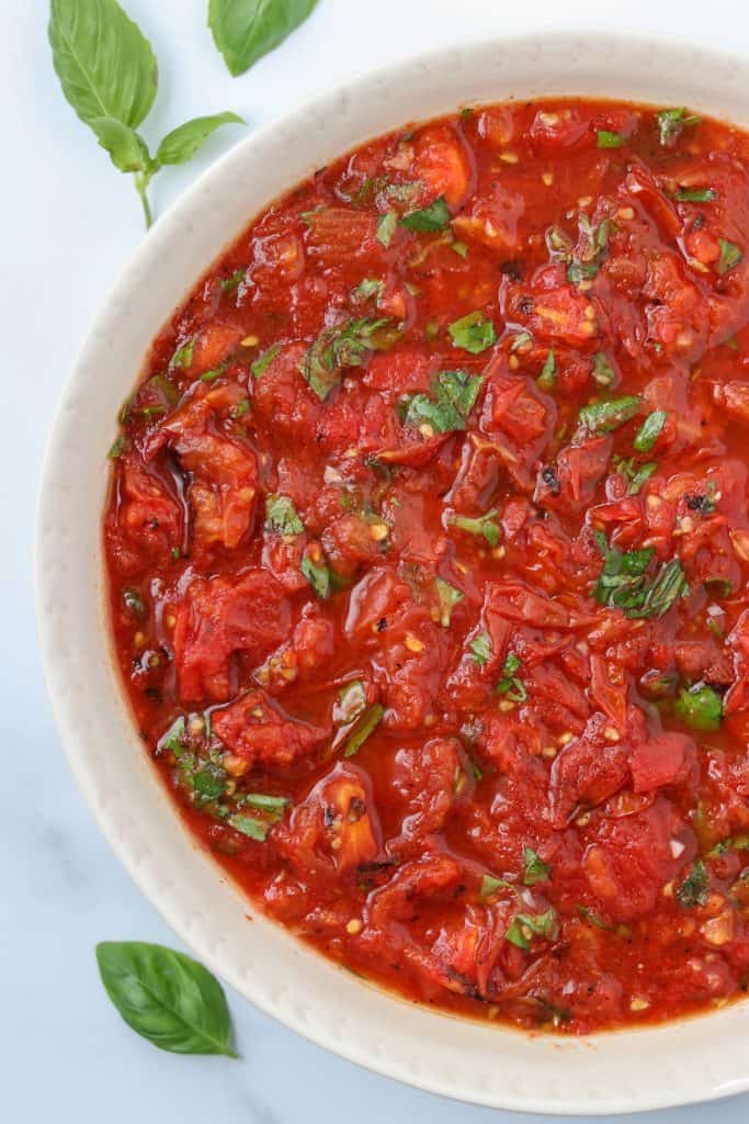 A bowl of grilled tomatoes with basil