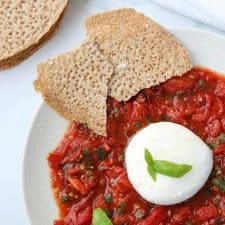 A plate with tomatoes, basil, burrata and crispbread