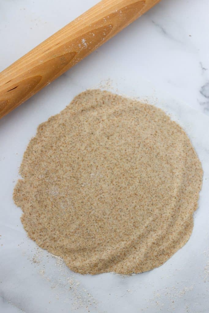 A piece of rolled out crispbread dough and a rolling pin