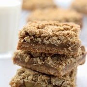 A close up of a stack of apple crumble bars with a glass of milk