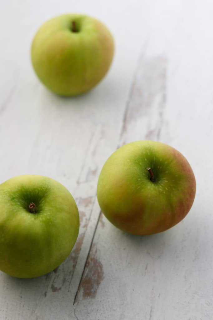 Three green apples on wooden surface