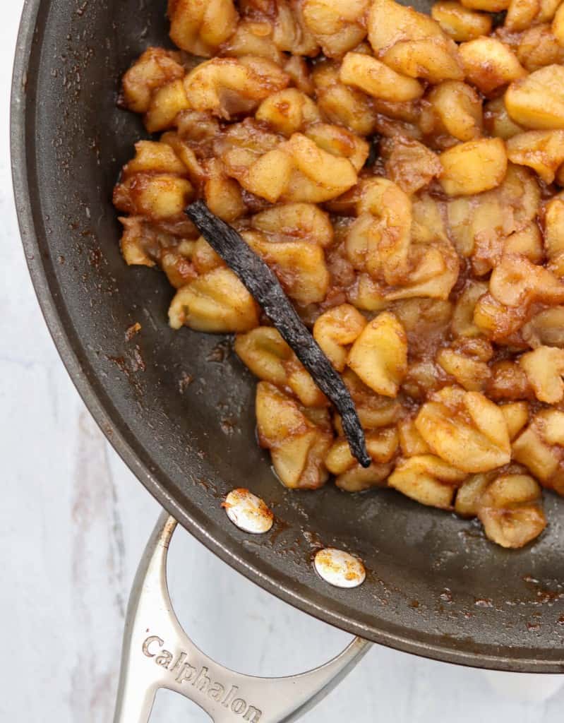Caramelized apple compote and a vanilla bean in a skillet