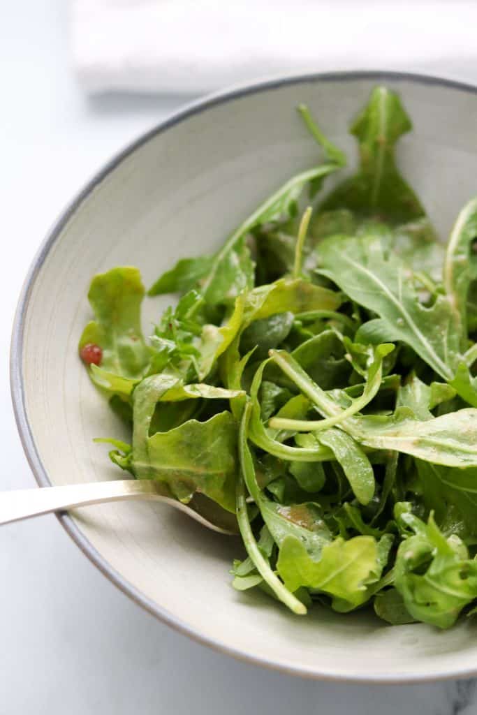 Arugula salad in a bowl with a fork