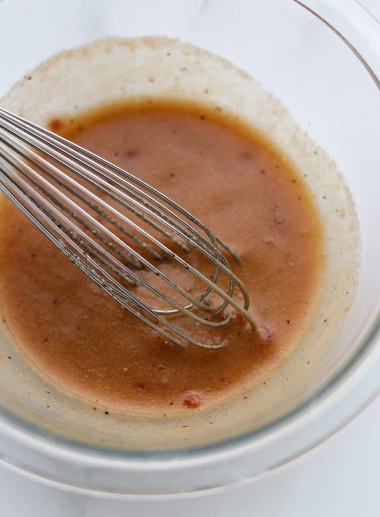 A bowl of vinaigrette with a whisk