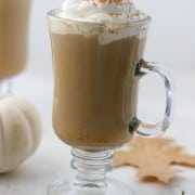 Pumpkin spice latte in a glass mug with fall leaves
