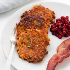 Crispy Sweet Potato Pancakes with Lingonberry Preserves and Bacon on a plate
