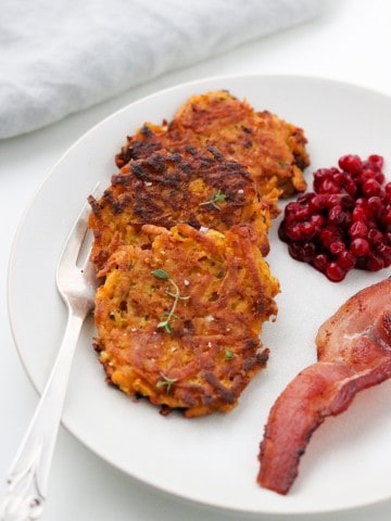 Crispy Sweet Potato Pancakes with Lingonberry Preserves and Bacon on a plate