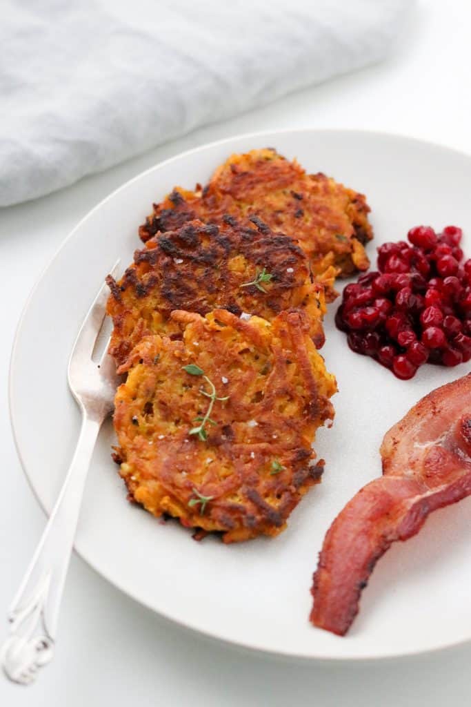 Crispy Sweet Potato Pancakes with Lingonberry Preserves and Bacon on a plate