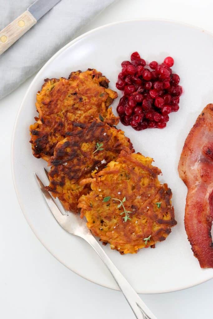 Crispy Sweet Potato Pancakes with Lingonberry Preserves and Bacon on a plate