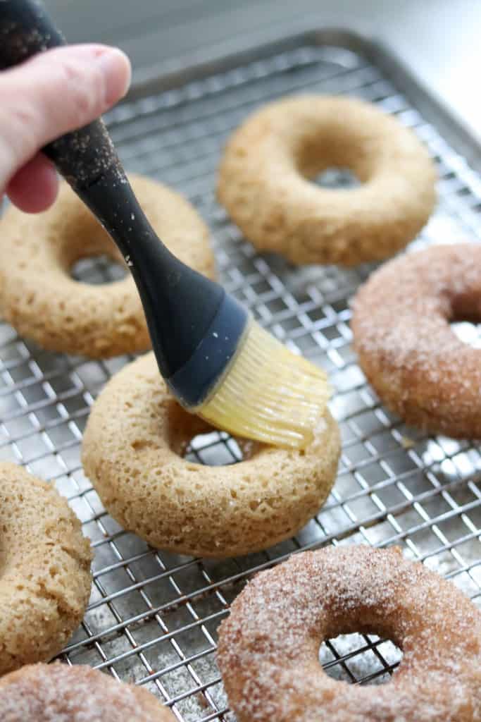 Close up of person brushing butter onto a donut