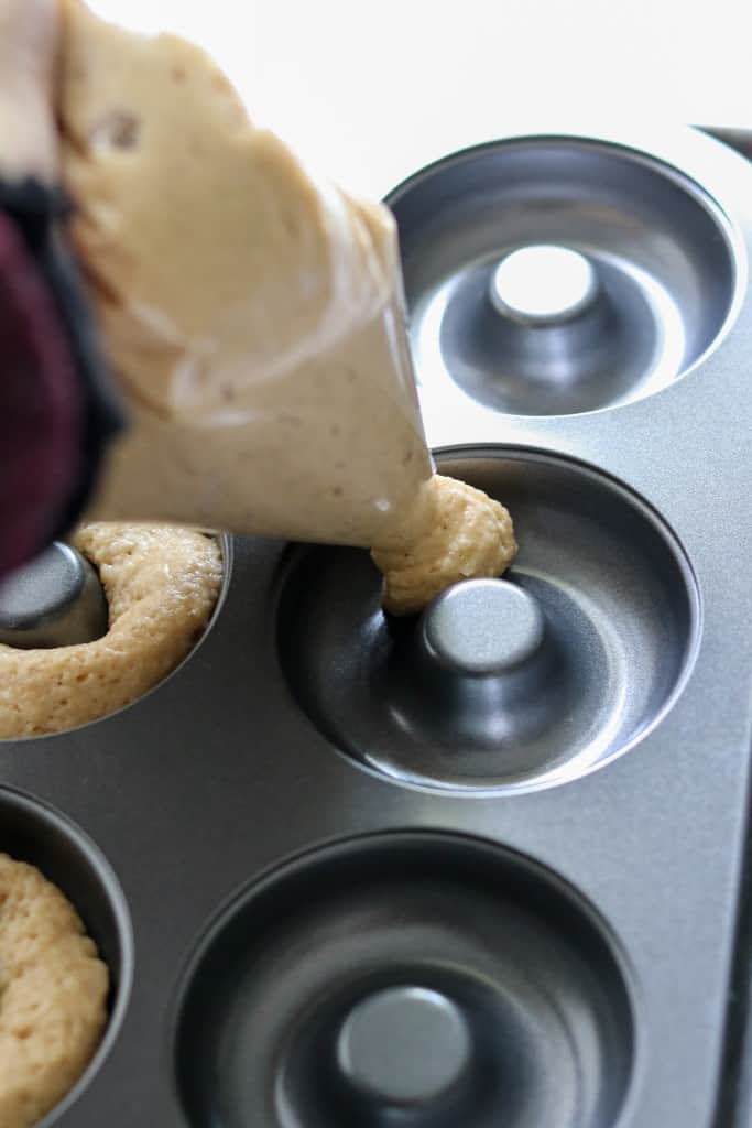 Close up of person squeezing donut batter into a pan