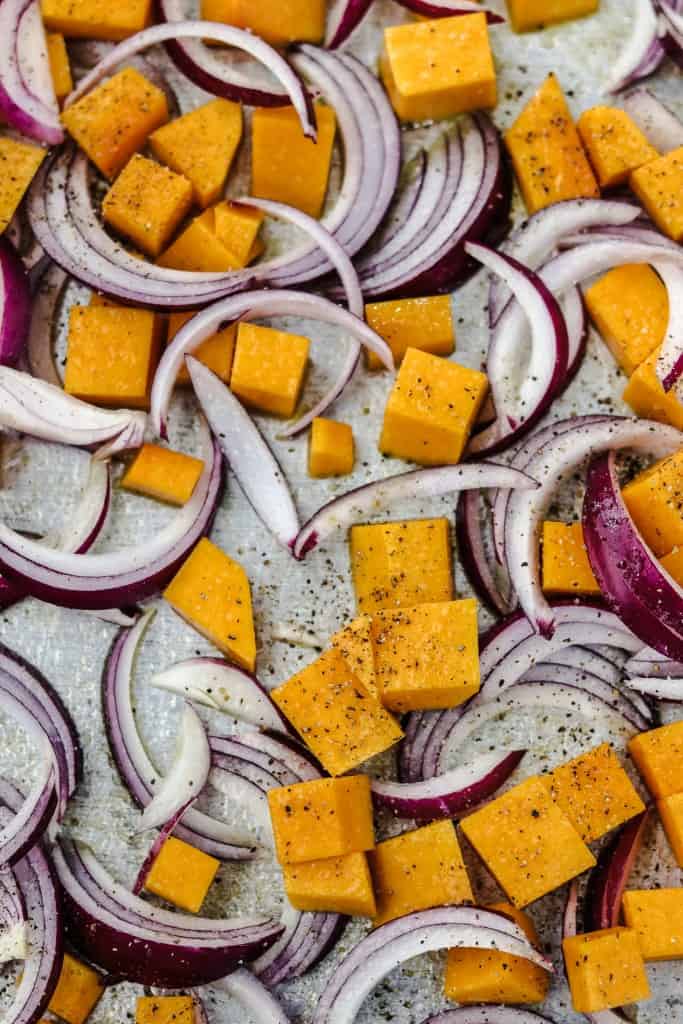 Cubes of butternut squash and red onion slices on a sheet pan