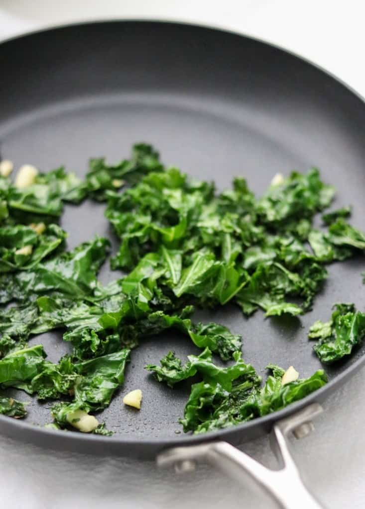 kale and garlic cooking in a skillet