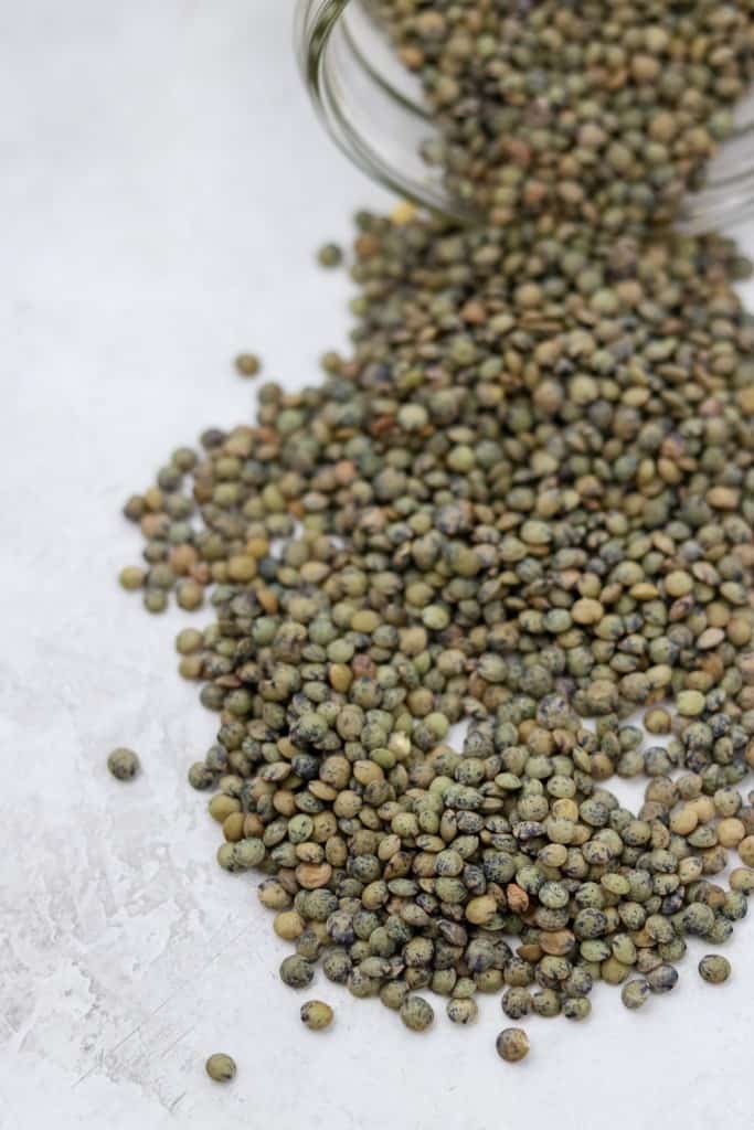 Jar of lentils spilled onto a concrete surface