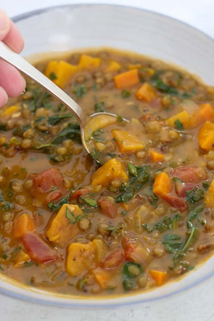 a close up of Hearty Lentil Soup with Roasted Butternut Squash, Kale and Bacon in a bowl with a spoon