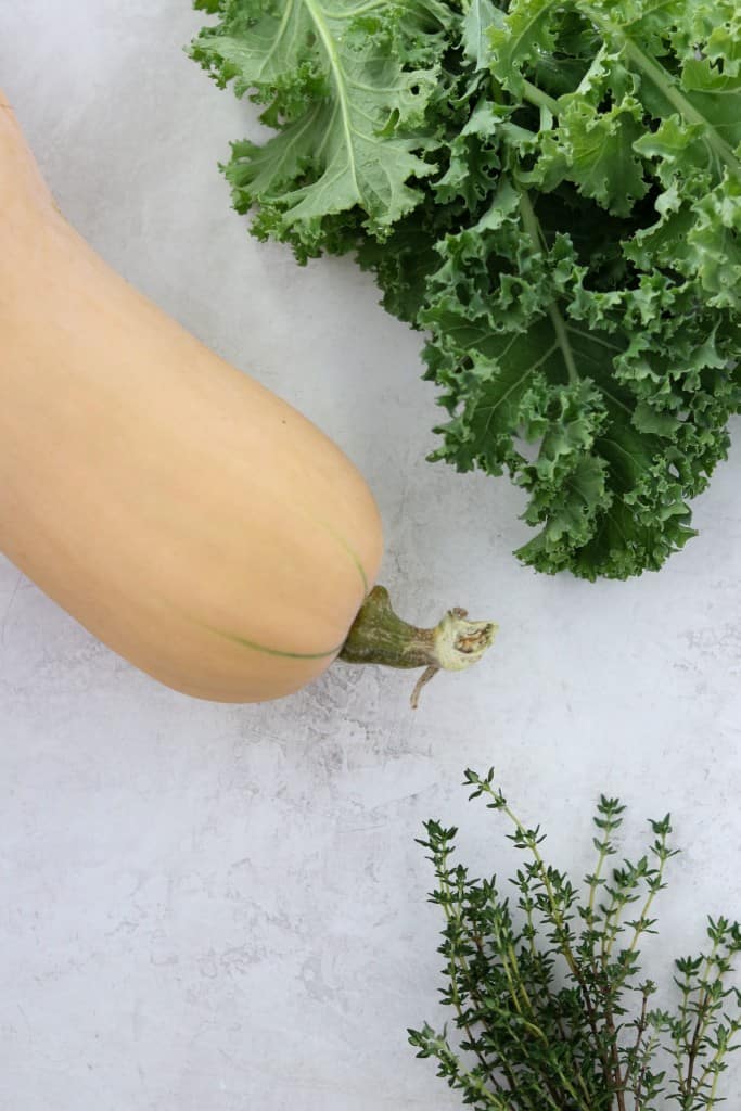 Butternut squash, kale and thyme on a concrete surface