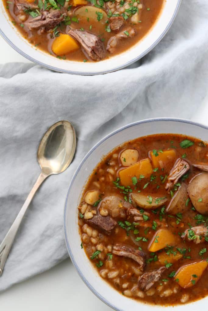 Bowl of beef stew next to a spoon and napkin