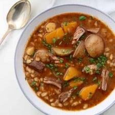 Bowl of beef stew next to a spoon and napkin