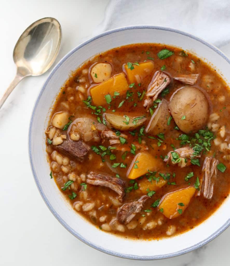 Bowl of beef stew next to a spoon and napkin