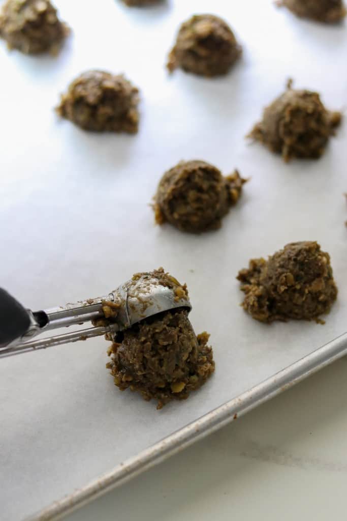 A close up of someone scooping a vegetarian meatball mixture onto a baking sheet