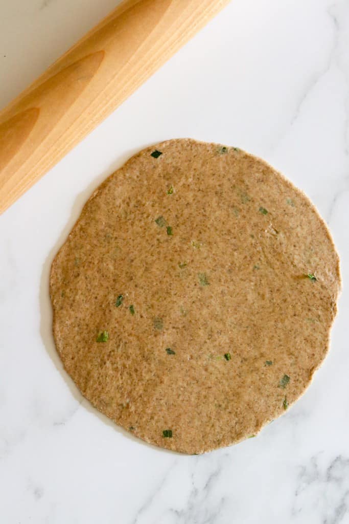 Flatbread dough rolled out on a counter with a rolling pin