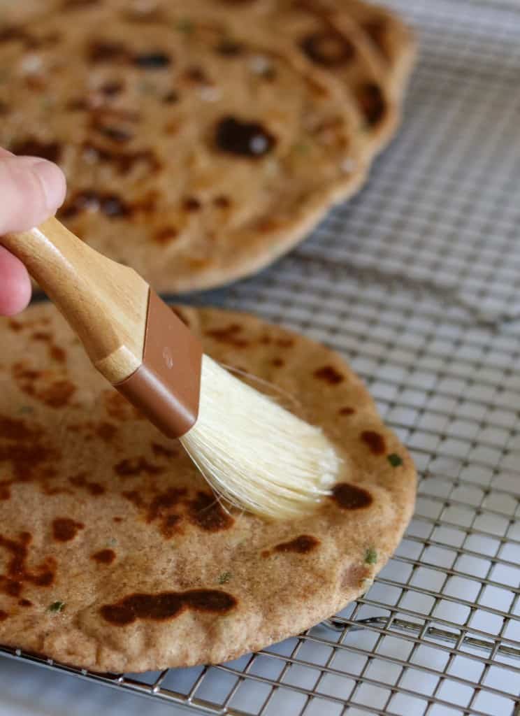 Person brushing a flatbread with butter