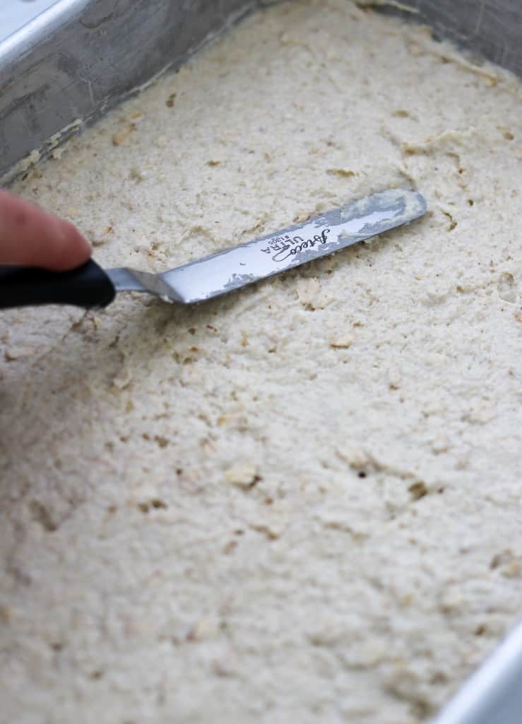 Person smoothing flatbread dough into a metal pan