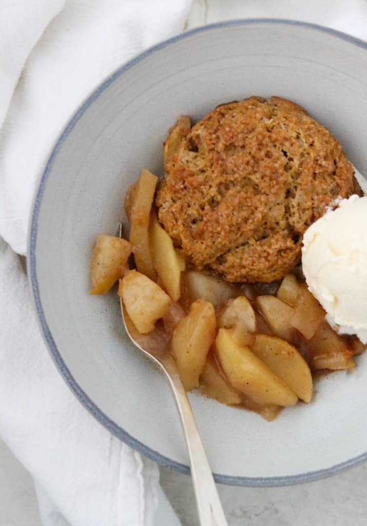 Gingerbread cobbler with apples and pears in a bowl with ice cream and a fork