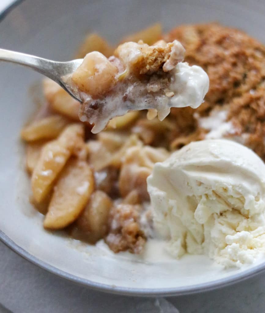 A close up of a bite of gingerbread cobbler with ice cream