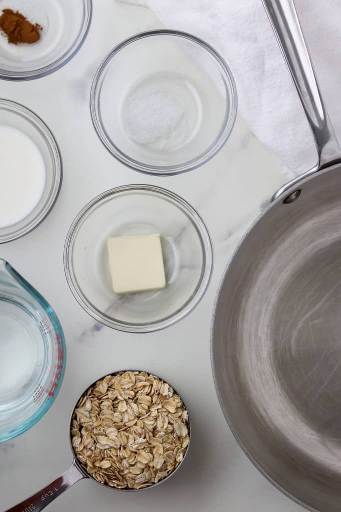 Oats, butter, milk and spices in small bowls next to a saucepan