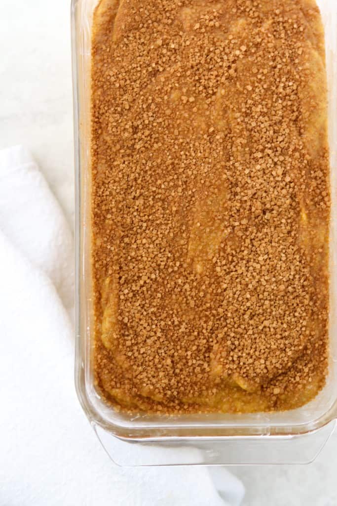 Pumpkin bread batter in a loaf pan next to a white towel