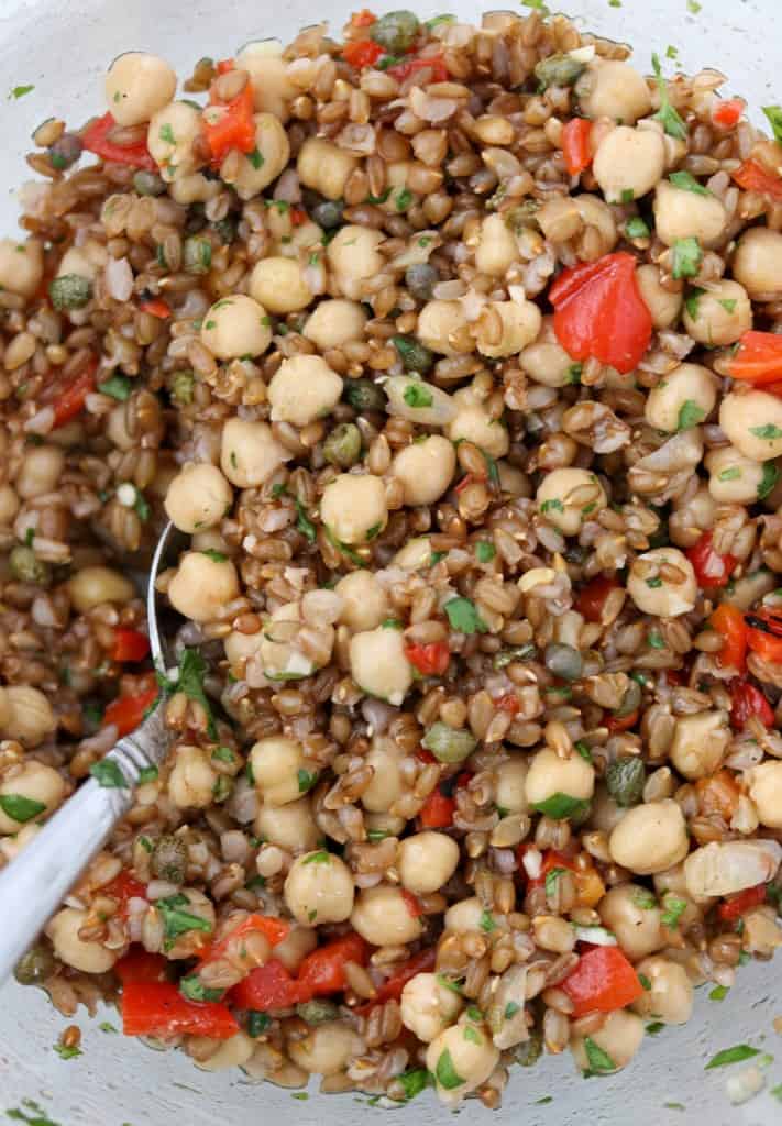 rye berries, chickpeas and roasted red peppers tossed together in a bowl with a spoon